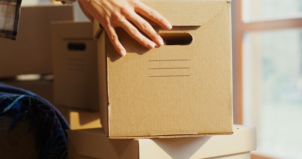 Person handling a cardboard box during organized product return process in bright workspace