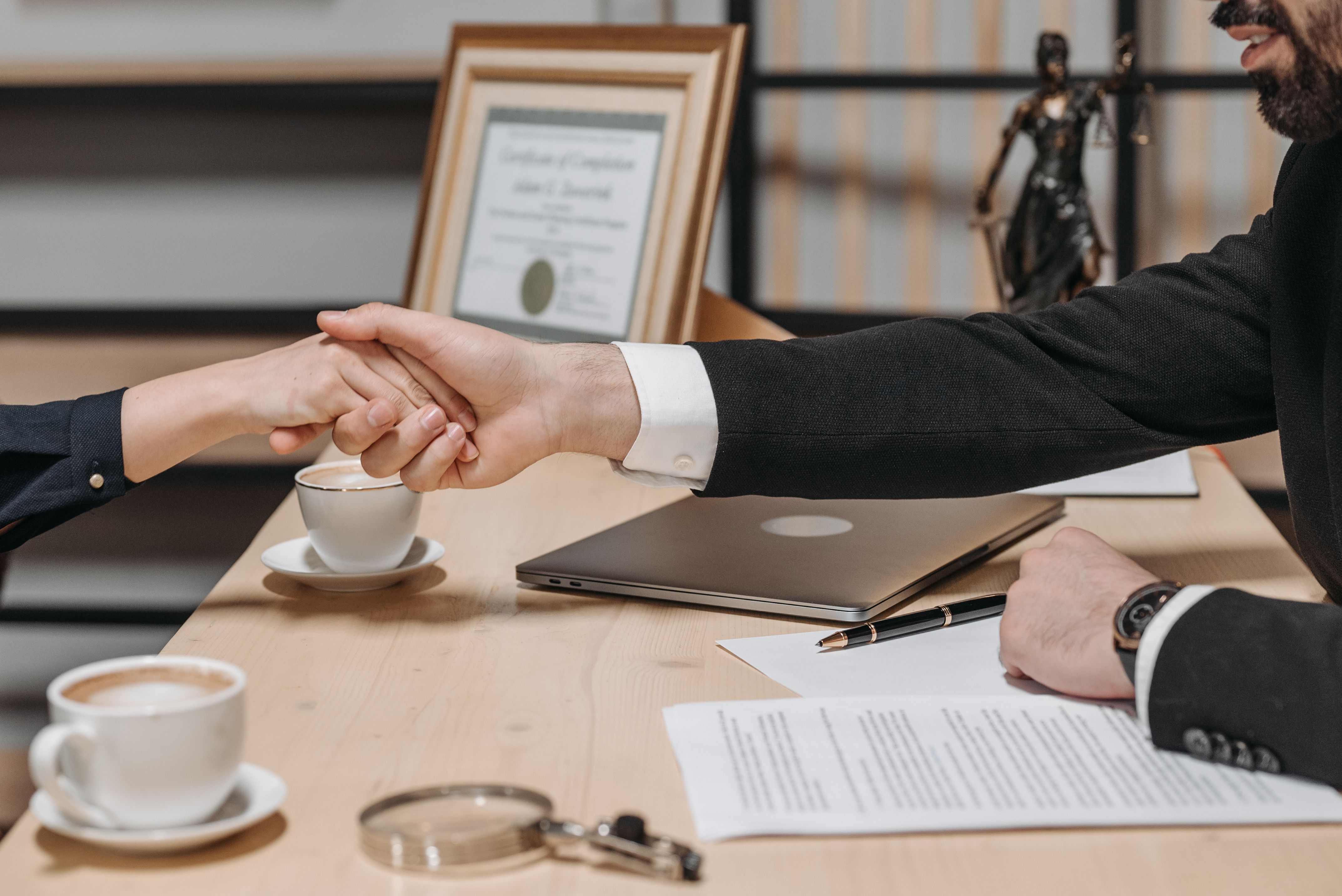 Business professionals sealing an agreement with a handshake over a contract.