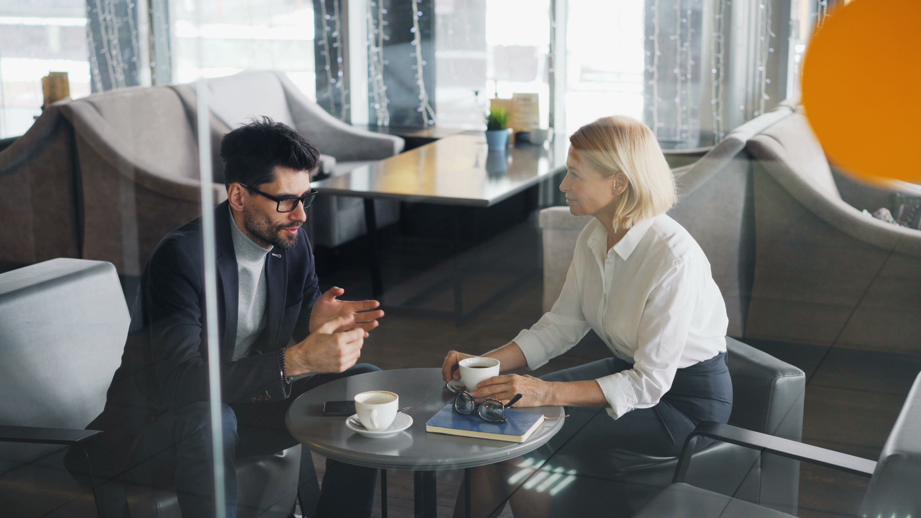 Business professionals discussing a specialized service over coffee in a modern office.