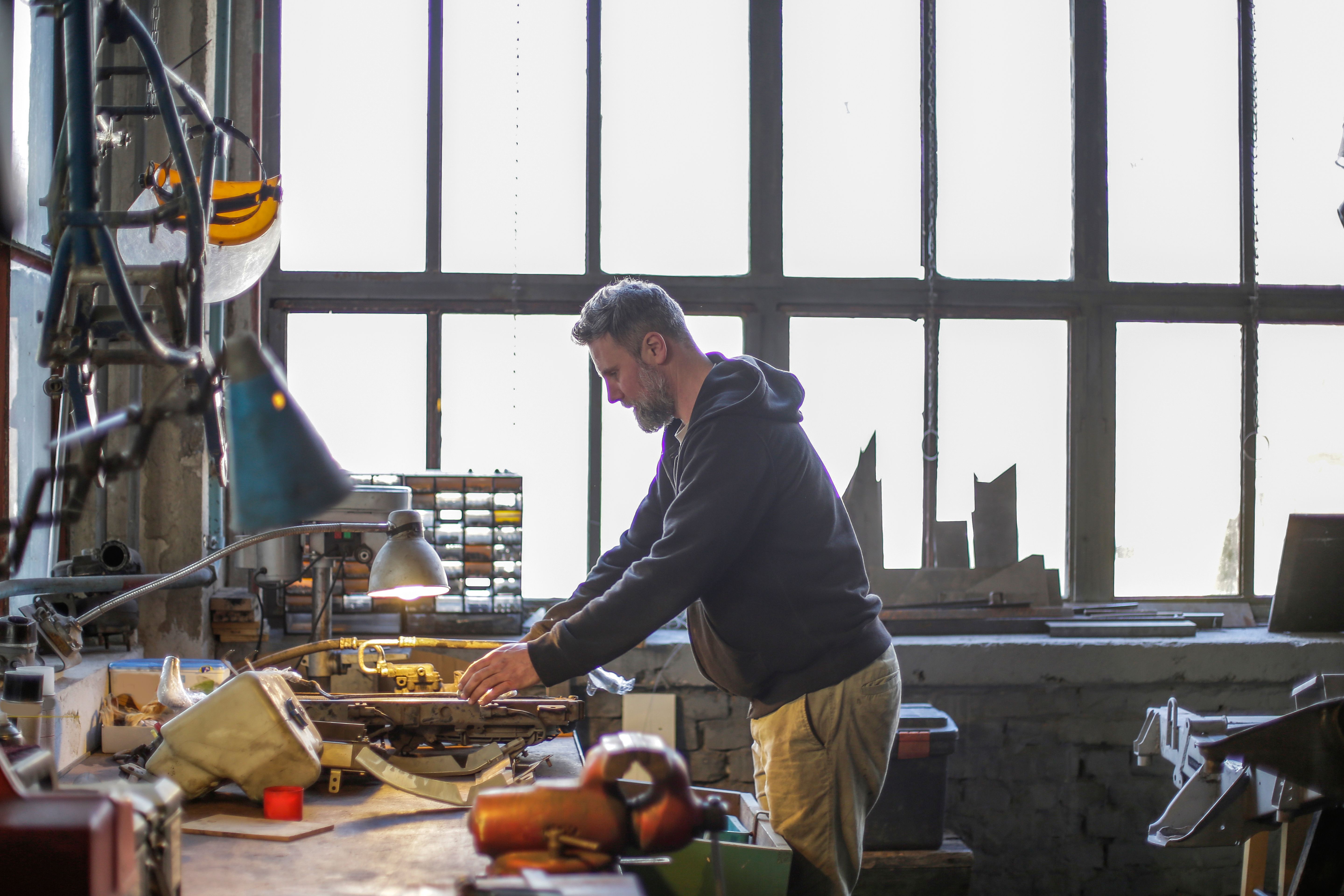 Skilled craftsperson using tools at a workbench in a specialized workshop.